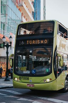 View of a double-decker tourist bus passing through the vibrant streets of Curitiba, Brazil.
