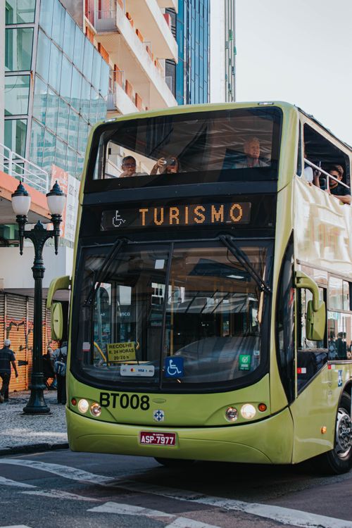 Free View of a double-decker tourist bus passing through the vibrant streets of Curitiba, Brazil. Stock Photo