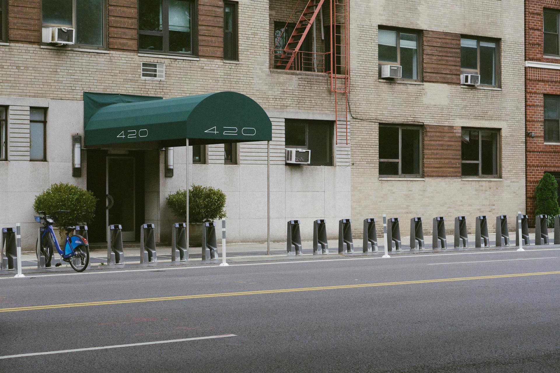 An urban street scene in New York City showing a building facade with a bike rack and green awning.