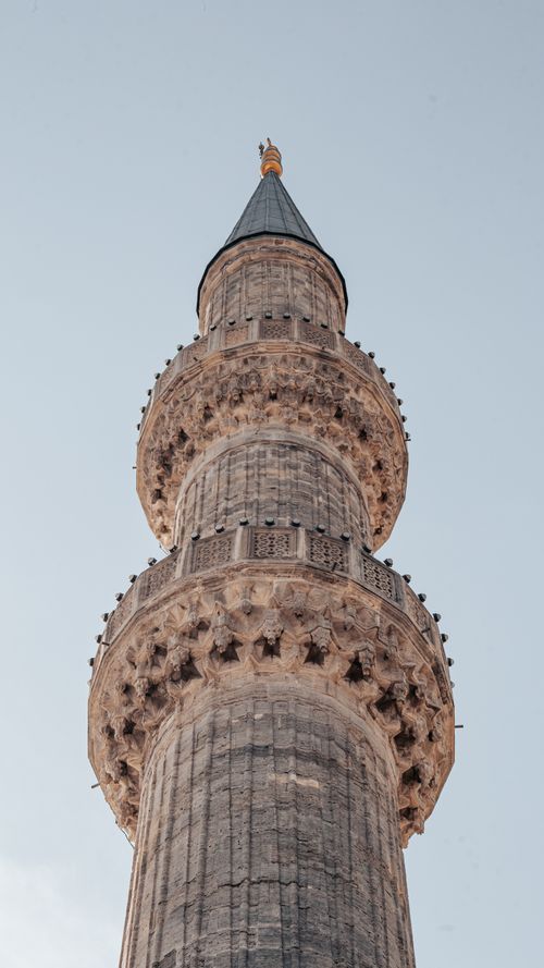 Free Low angle view of an Ottoman minaret in Istanbul, showcasing intricate architectural details against a blue sky. Stock Photo