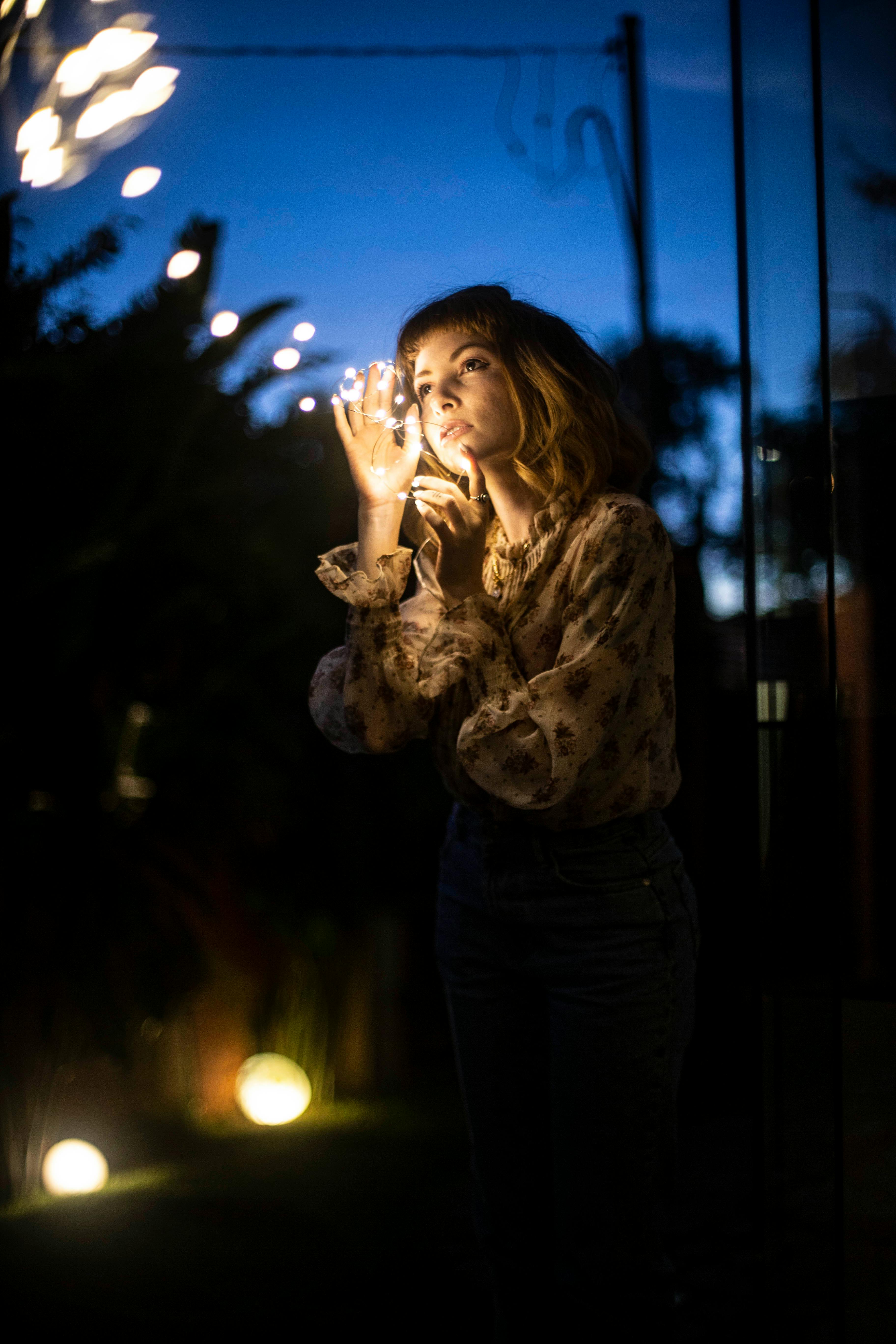 夜晚，一个女人在户外欣赏着发光的串灯，营造出宁静的气氛