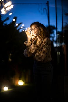 夜晚，一个女人在户外欣赏着发光的串灯，营造出宁静的气氛