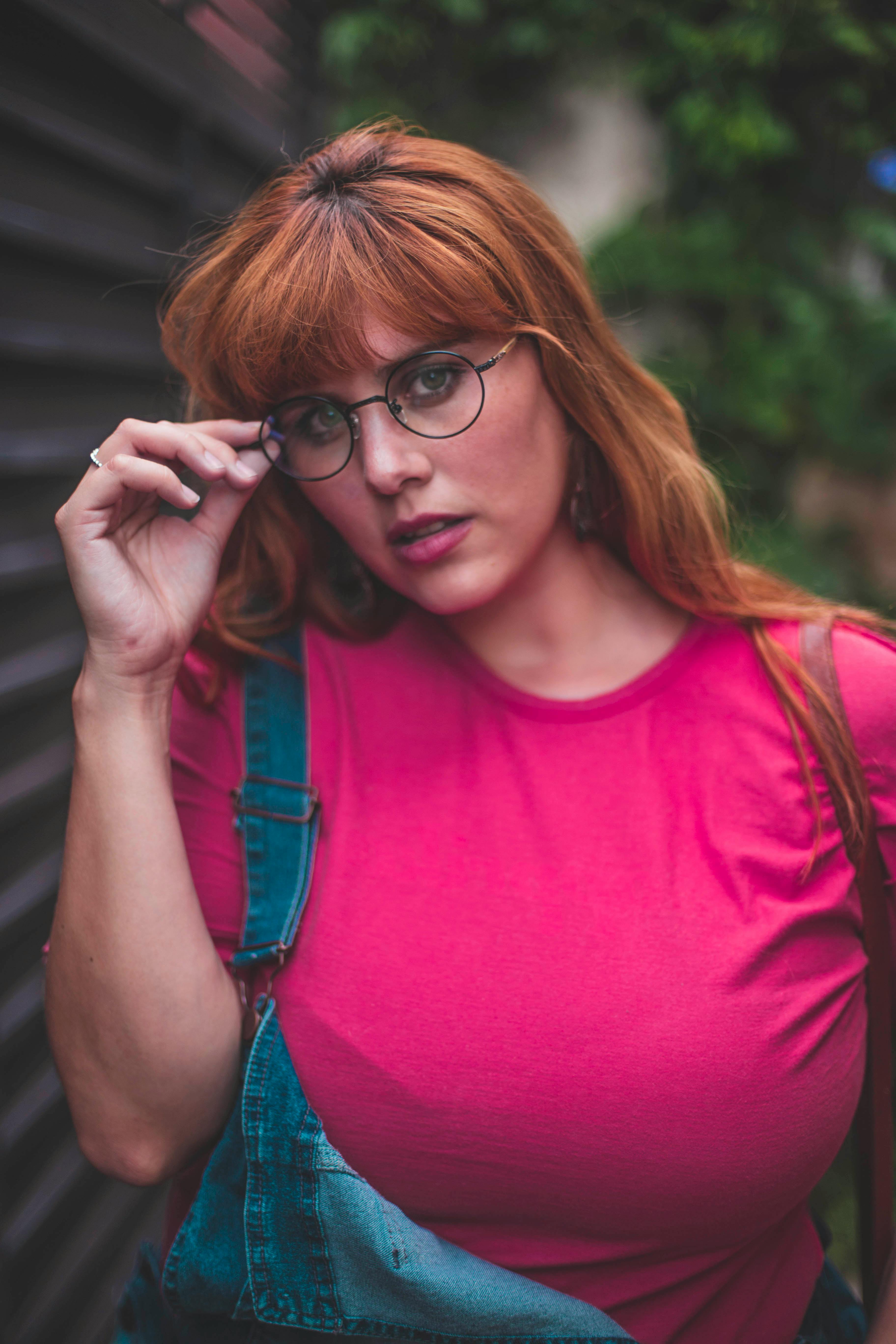 一位时尚女性戴着眼镜，身着休闲装，在户外摆出充满活力的姿势