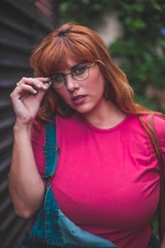 一位时尚女性戴着眼镜，身着休闲装，在户外摆出充满活力的姿势