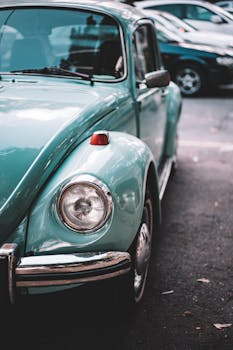 Close-up of a classic turquoise VW Beetle parked in an urban lot, showcasing vintage design.