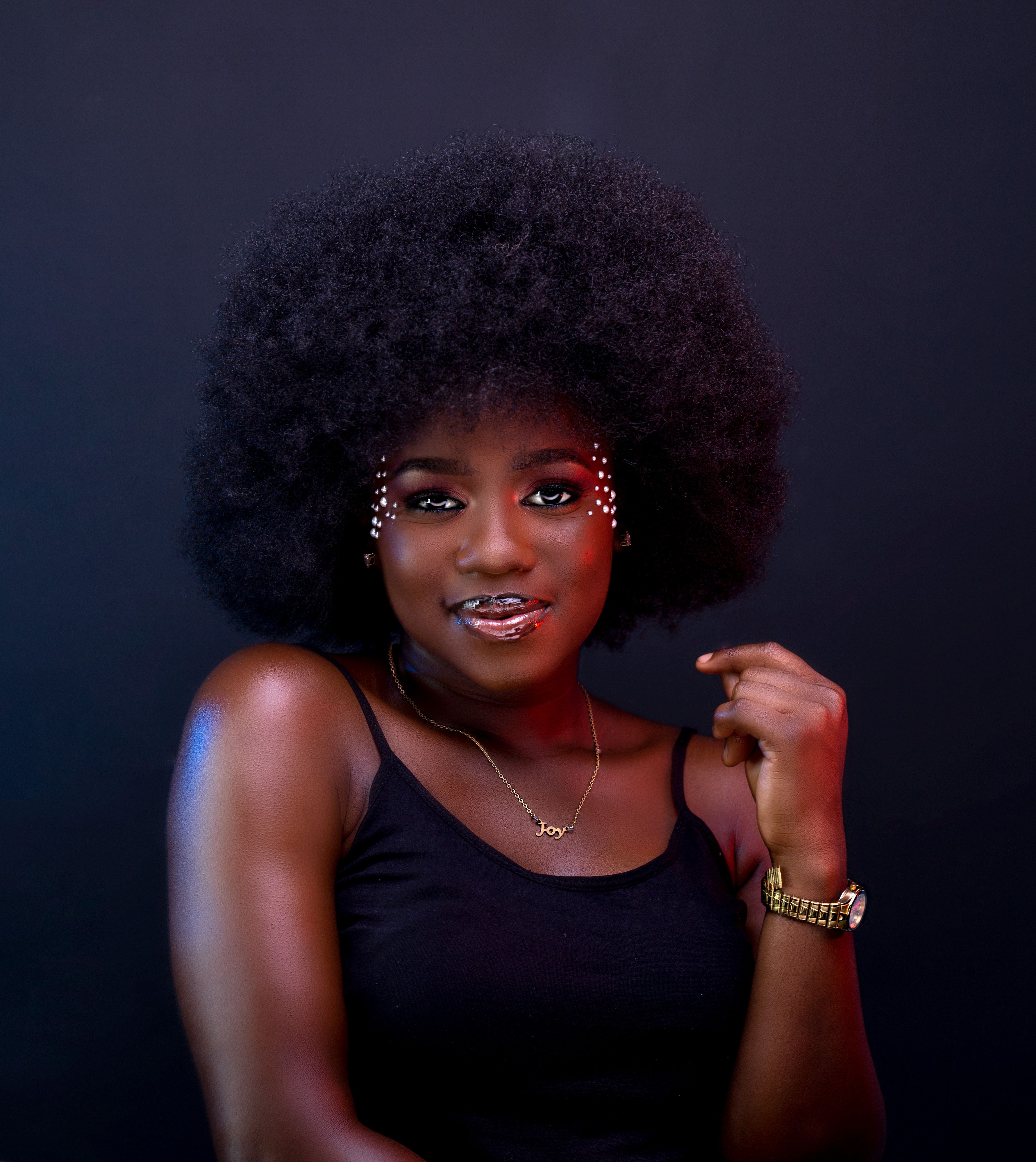 Glamorous studio portrait of a woman with afro hair wearing makeup and accessories.
