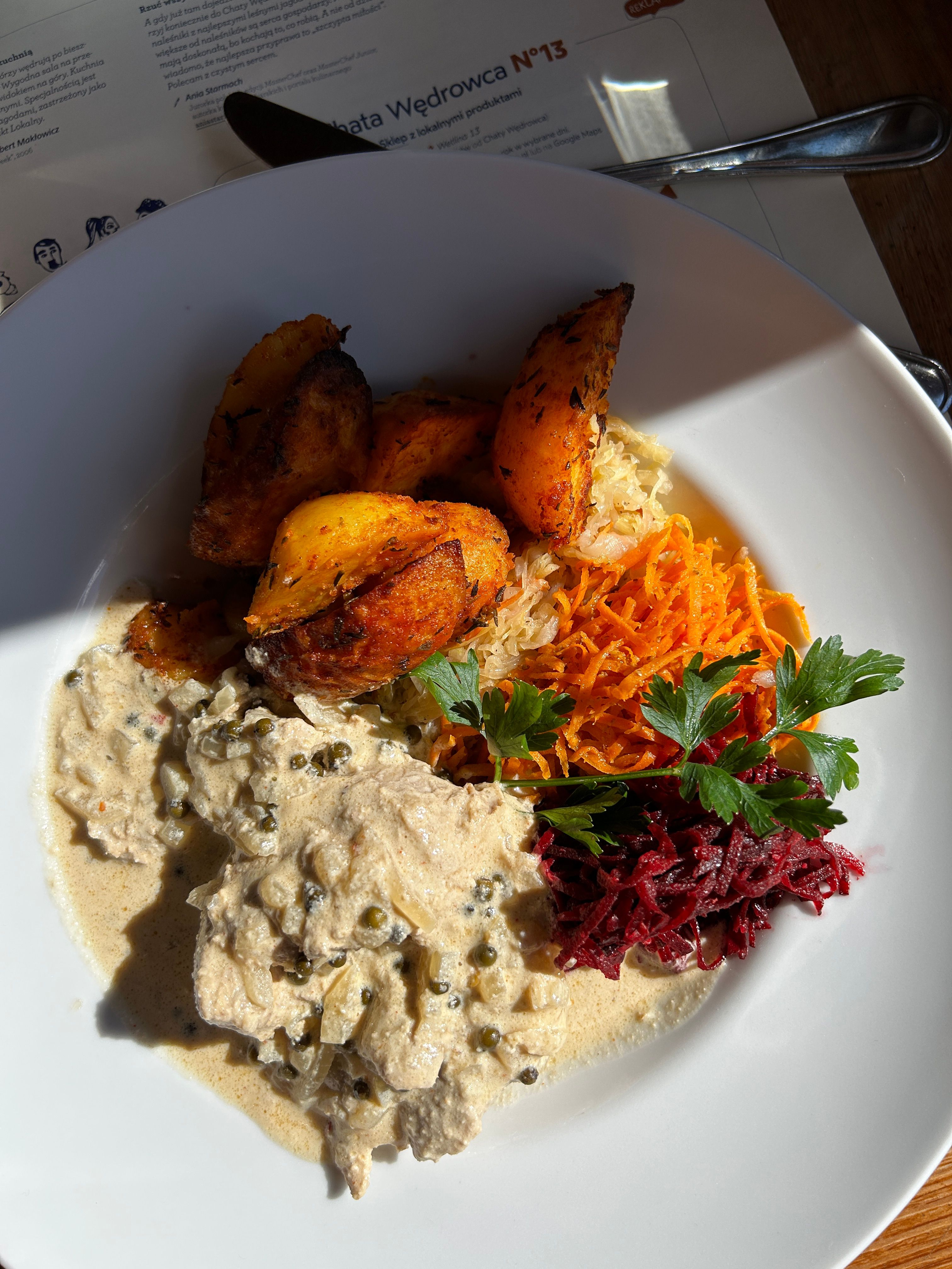 Appetizing plate showcasing creamy chicken, roasted potatoes, and colorful vegetables in a bright setting.