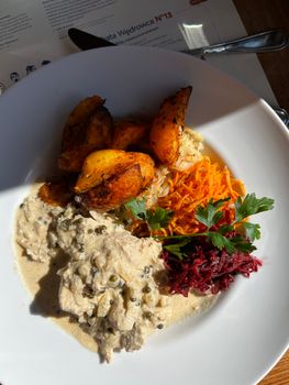 Appetizing plate showcasing creamy chicken, roasted potatoes, and colorful vegetables in a bright setting.