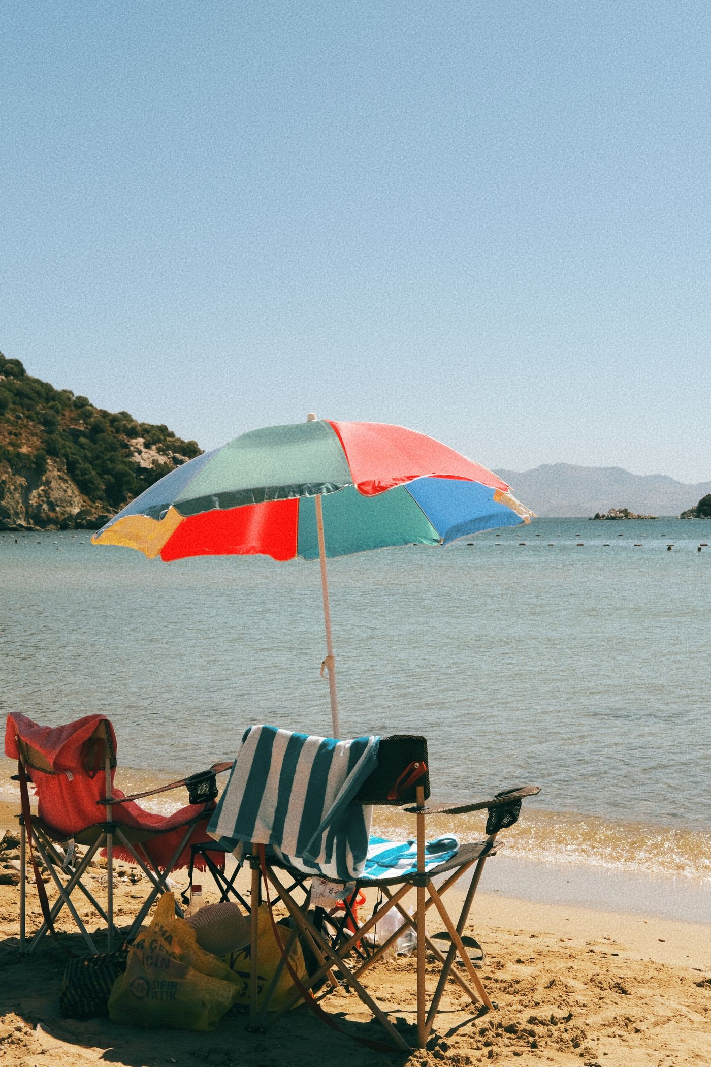 Beach umbrella and chairs arranged beside a calm ocean