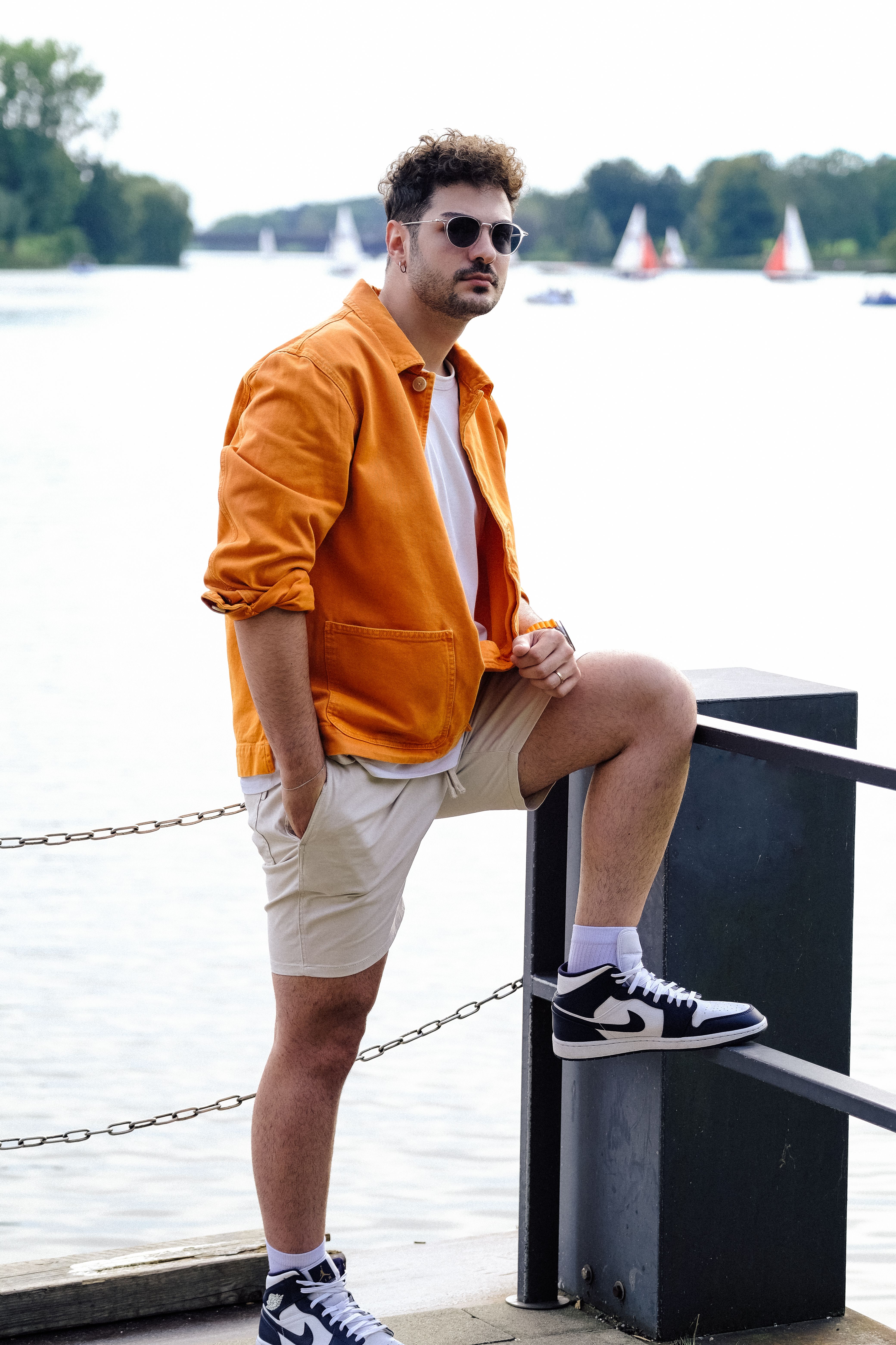 Man in Orange Shirt and Sunglasses Posing by Water · Free Stock Photo