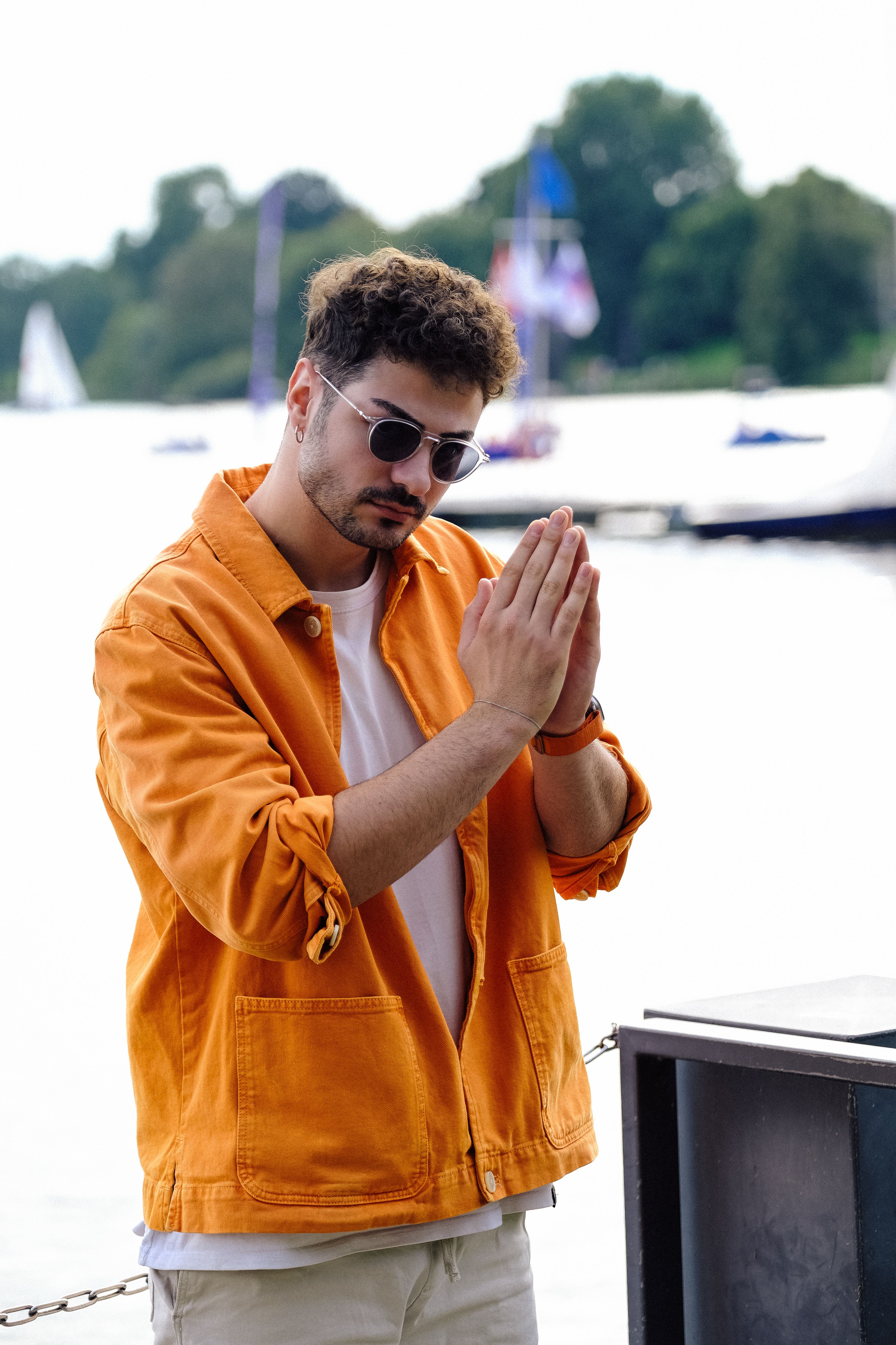 Man in Orange Shirt and Sunglasses Posing by Water · Free Stock Photo