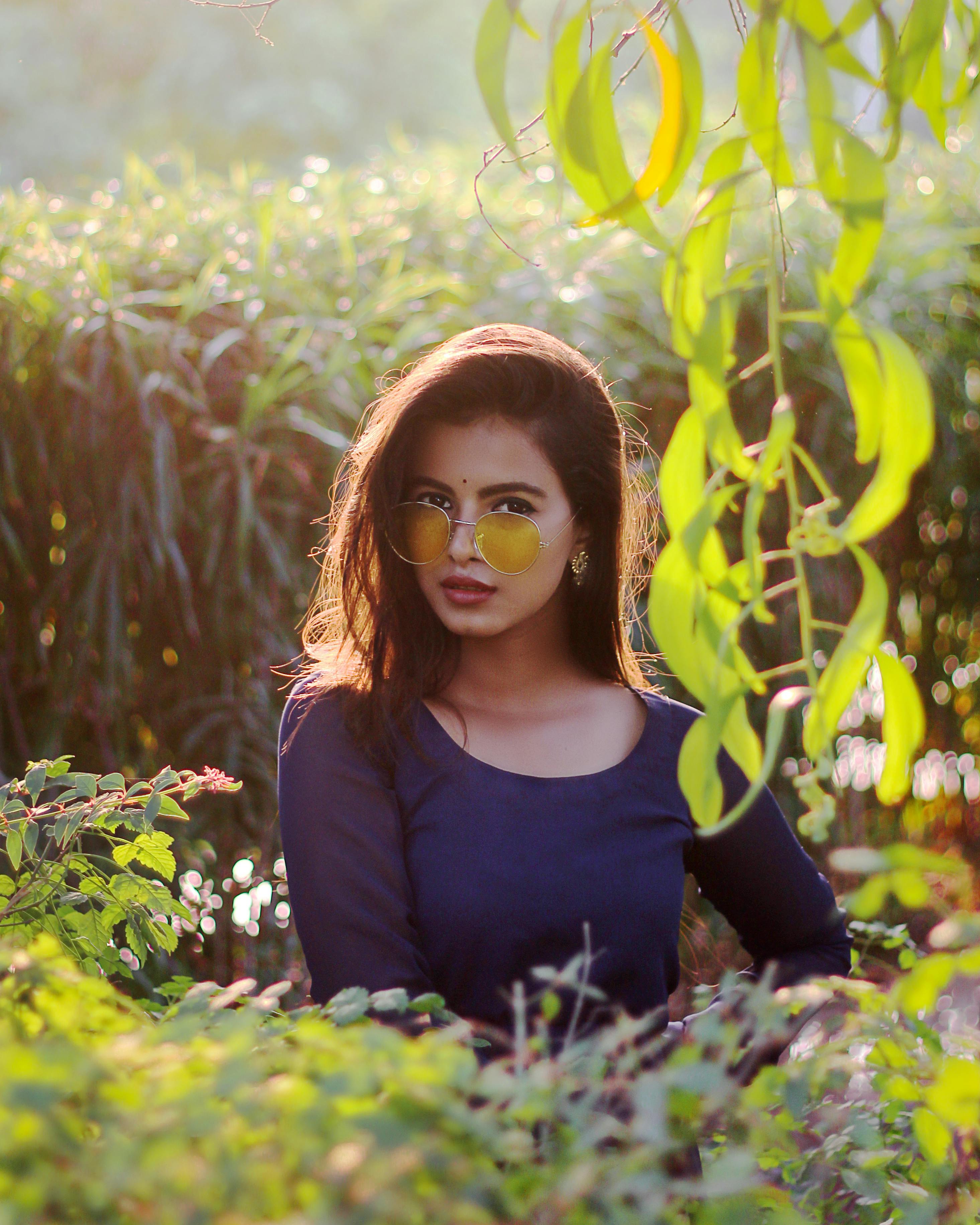 Woman standing behind leaves | Photo: Pexels