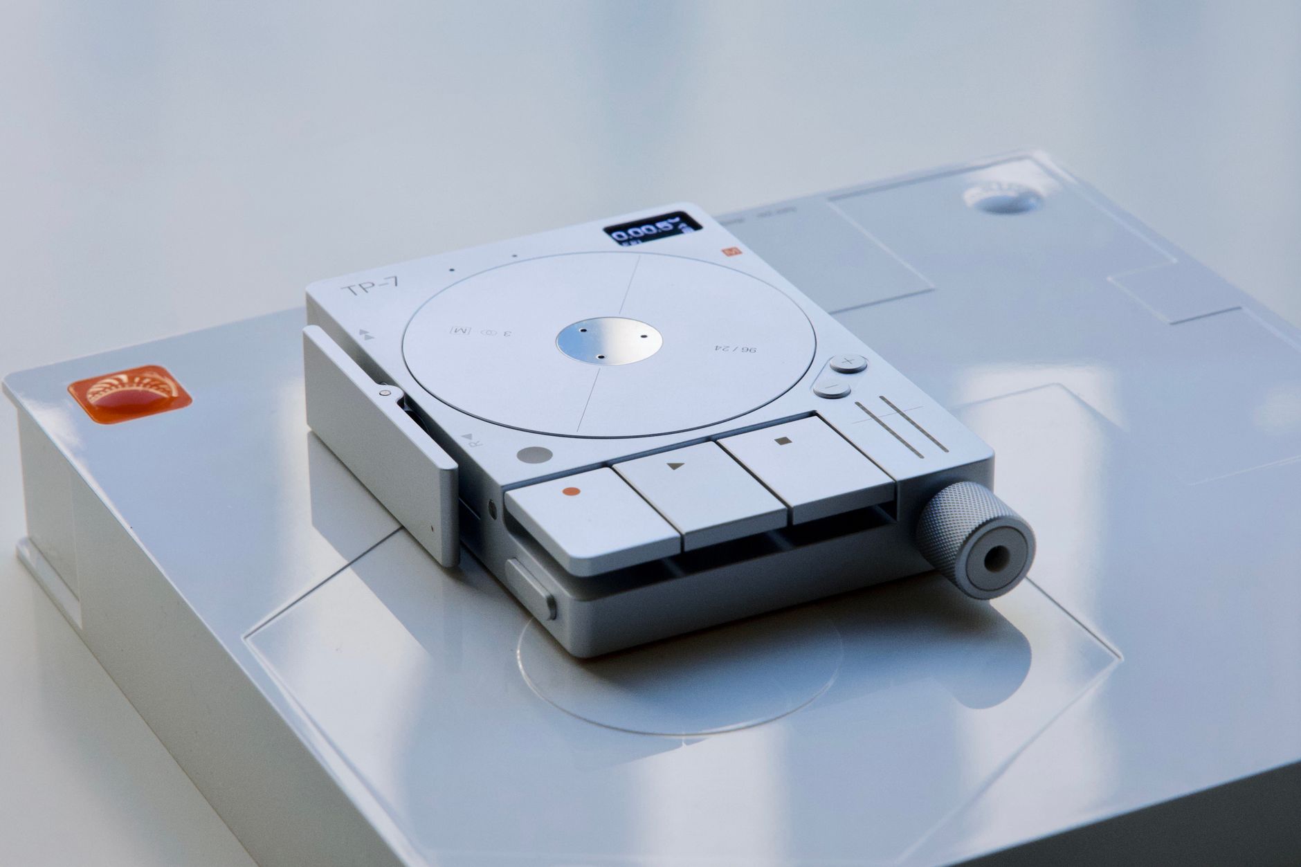Futuristic TP-7 digital audio recorder on a sleek white surface, emphasizing modern tech design.