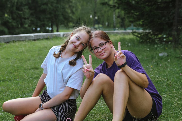 Smiling Girls Sitting On Grass In Park