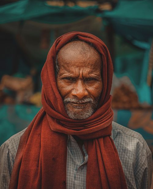 Free Portrait of an elderly man wearing a red scarf, standing firmly with a calm expression in Kota, India. Stock Photo