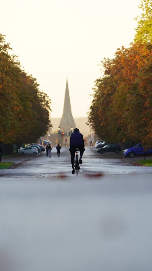 Man Cycling on Street in Autumn