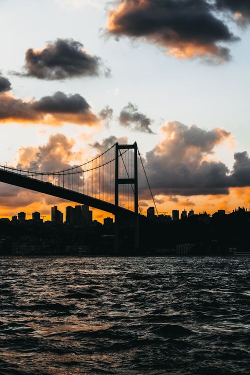 Free Silhouette of the Bosphorus Bridge with a vibrant sunset and cityscape in the background. Stock Photo