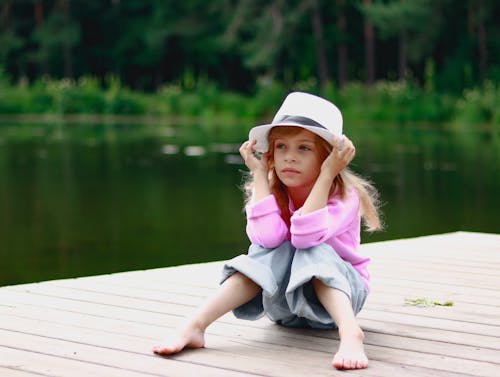 Girl in Hat Sitting on Pier