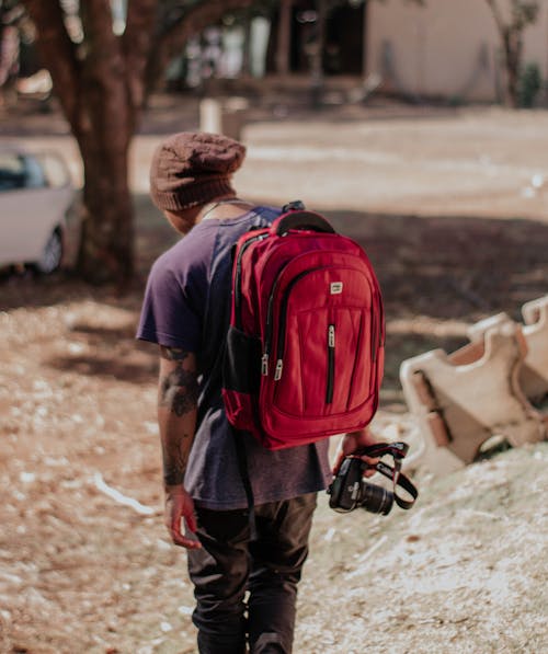 Man Holding Camera Using Red Backpack