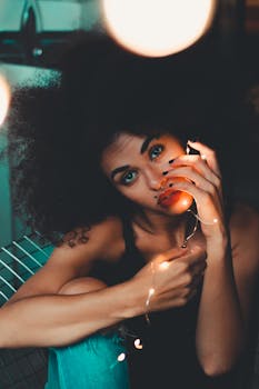 一位有着非洲裔发型、姿态优雅的美丽女子，在室内手持灯串的肖像