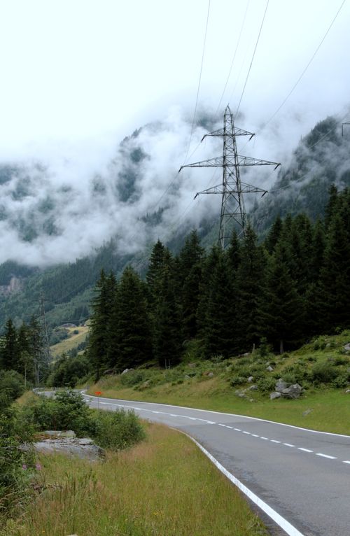 Free Curving road through a foggy mountain forest landscape, with power lines and lush greenery. Stock Photo