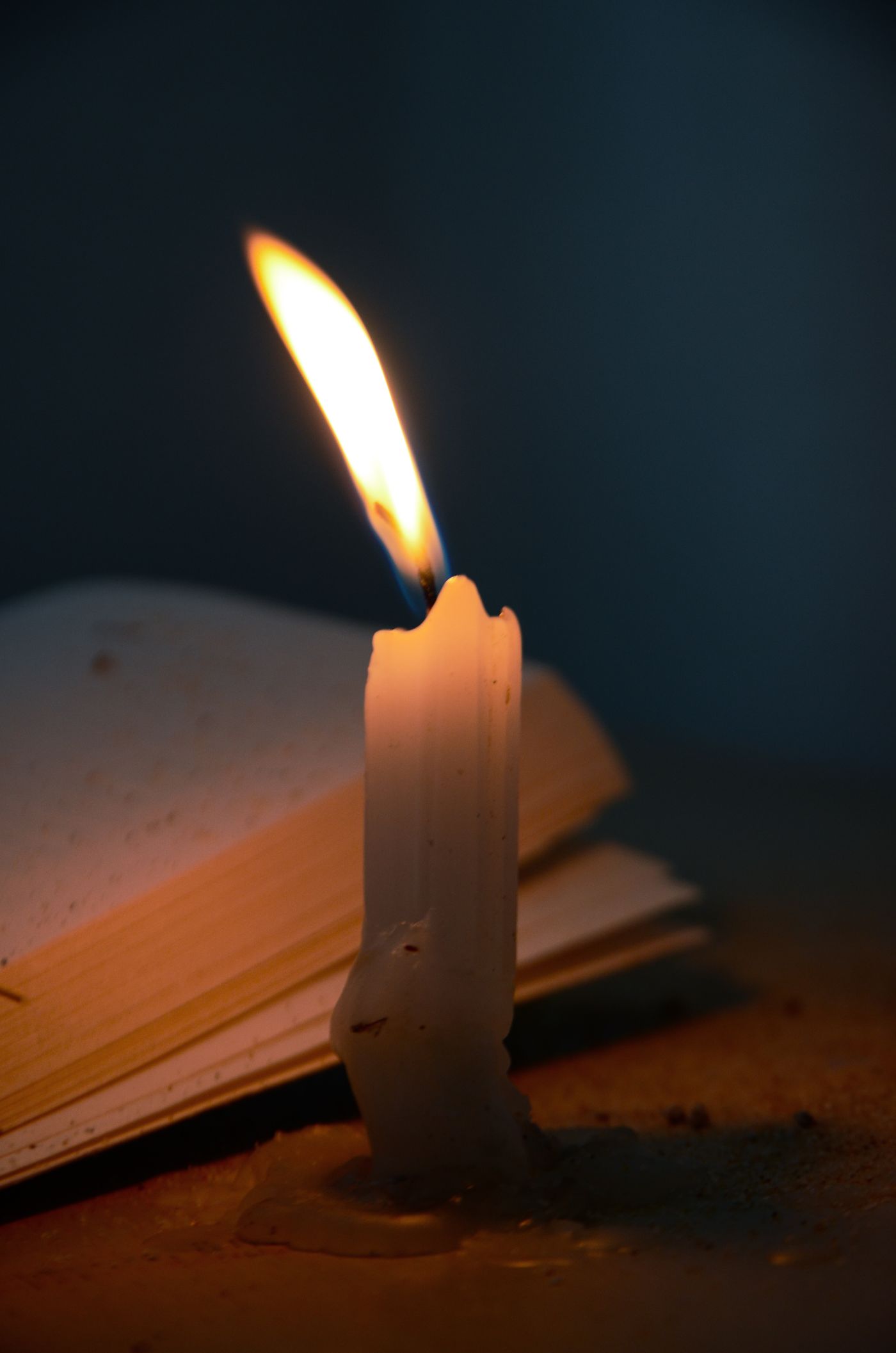 A burning candle on a desk in low light