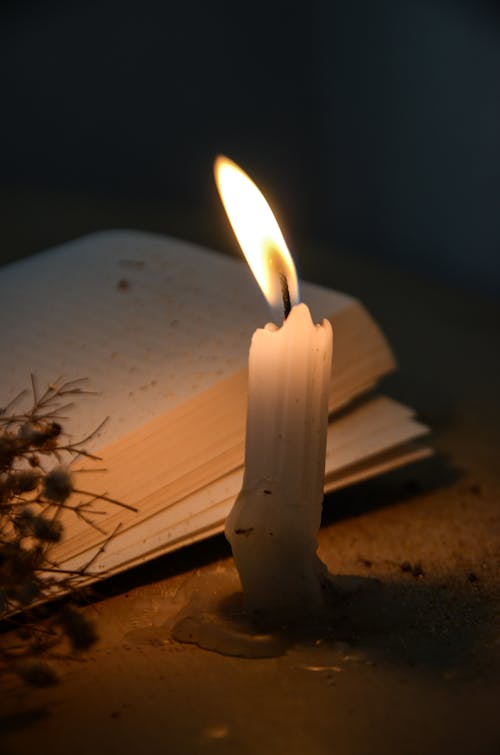 Lit Candle Next to an Open Book