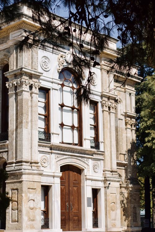 Free Beautiful historical building with ornate facade and large wooden doors, framed by trees. Stock Photo
