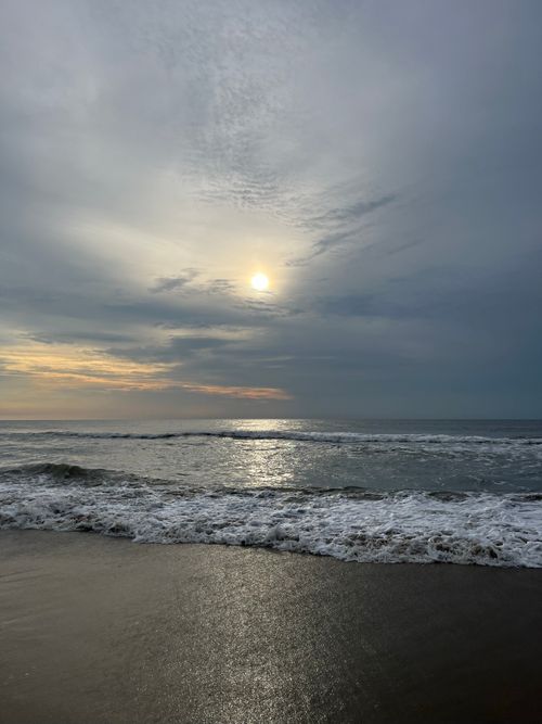 Free Tranquil beach scene at sunset with gentle waves and soft sunlight. Stock Photo