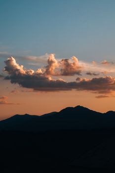 A stunning capture of mountains silhouetted against a vibrant sunset sky with clouds.