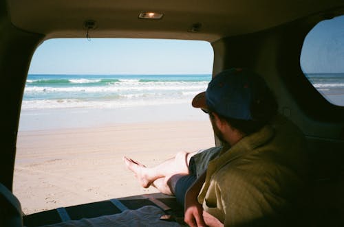 Man Lying Down and Relaxing in Car Trunk on Beach