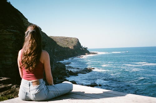 Woman Sitting on Wall on Sea Shore