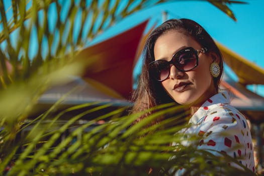 一位时尚女性戴着太阳镜和印花上衣，身处充满活力的户外环境中