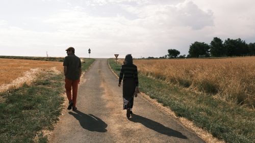 Free A man and woman walking on a rural road between fields on a sunny day. Stock Photo