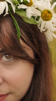 Close-up of a woman's face adorned with daisies in her hair, capturing natural beauty.
