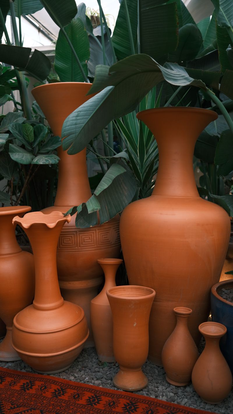 Large terracotta urns and vases standing among green palm leaves
