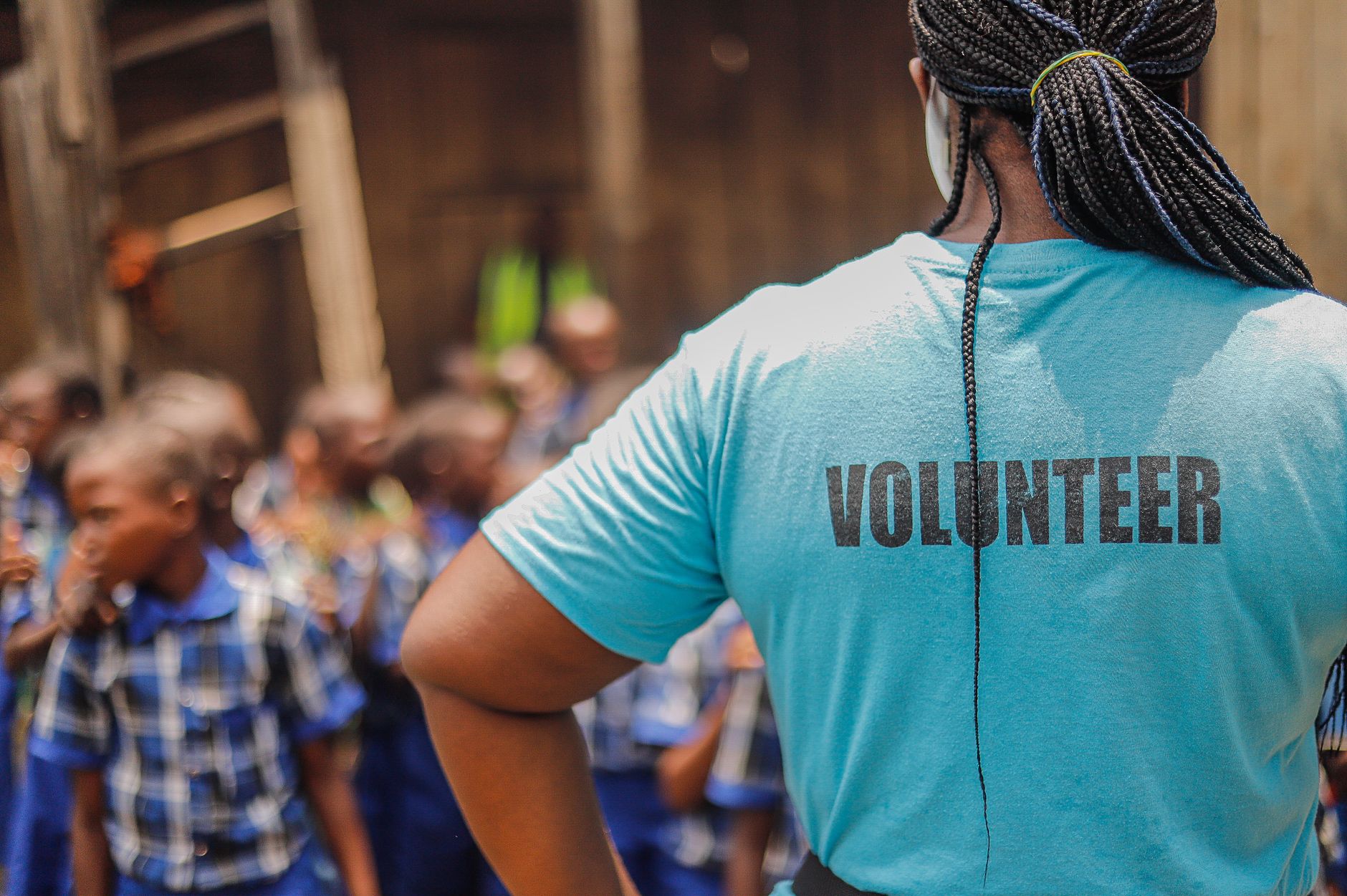 A volunteer interacts with children in a village school setting, fostering community support and development.