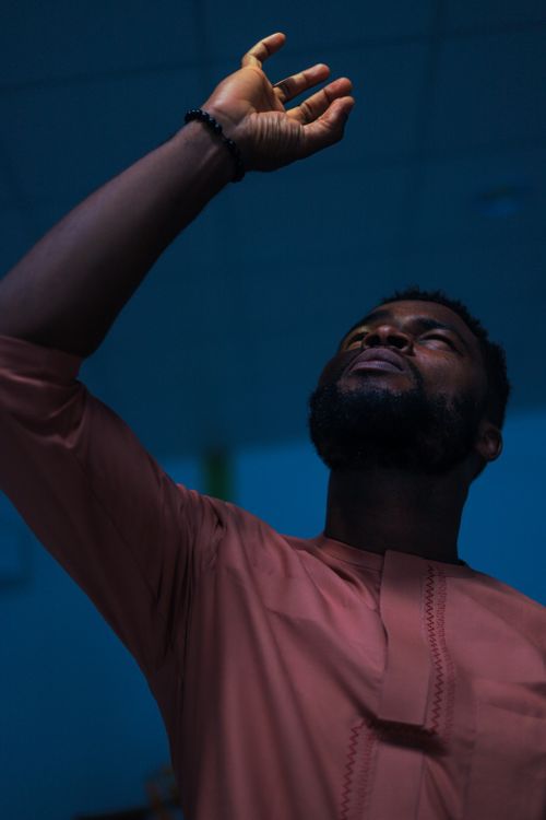 Free Portrait of a bearded man in traditional clothing gazing upward thoughtfully, with a raised hand. Stock Photo