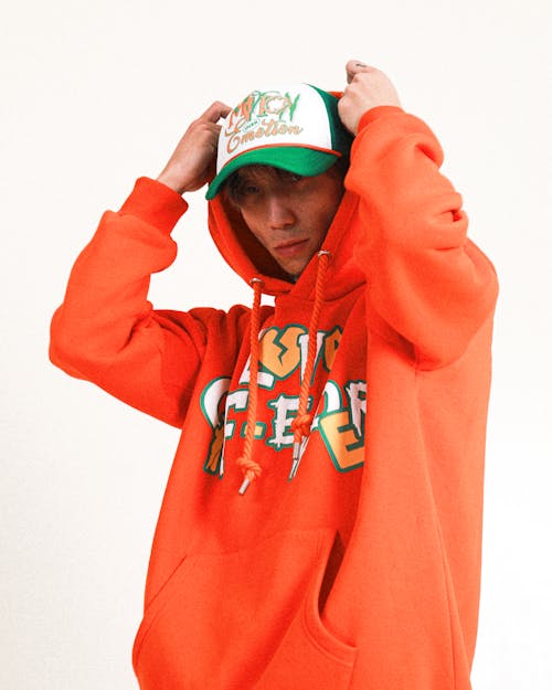 Man Posing in Orange Hooded Sweatshirt and Baseball Cap