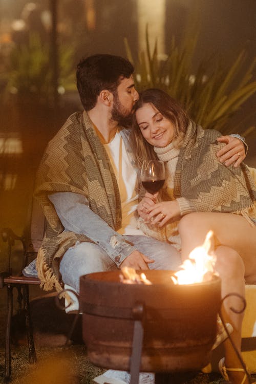 Couple Cuddling on a Bench by the Campfire Cauldron