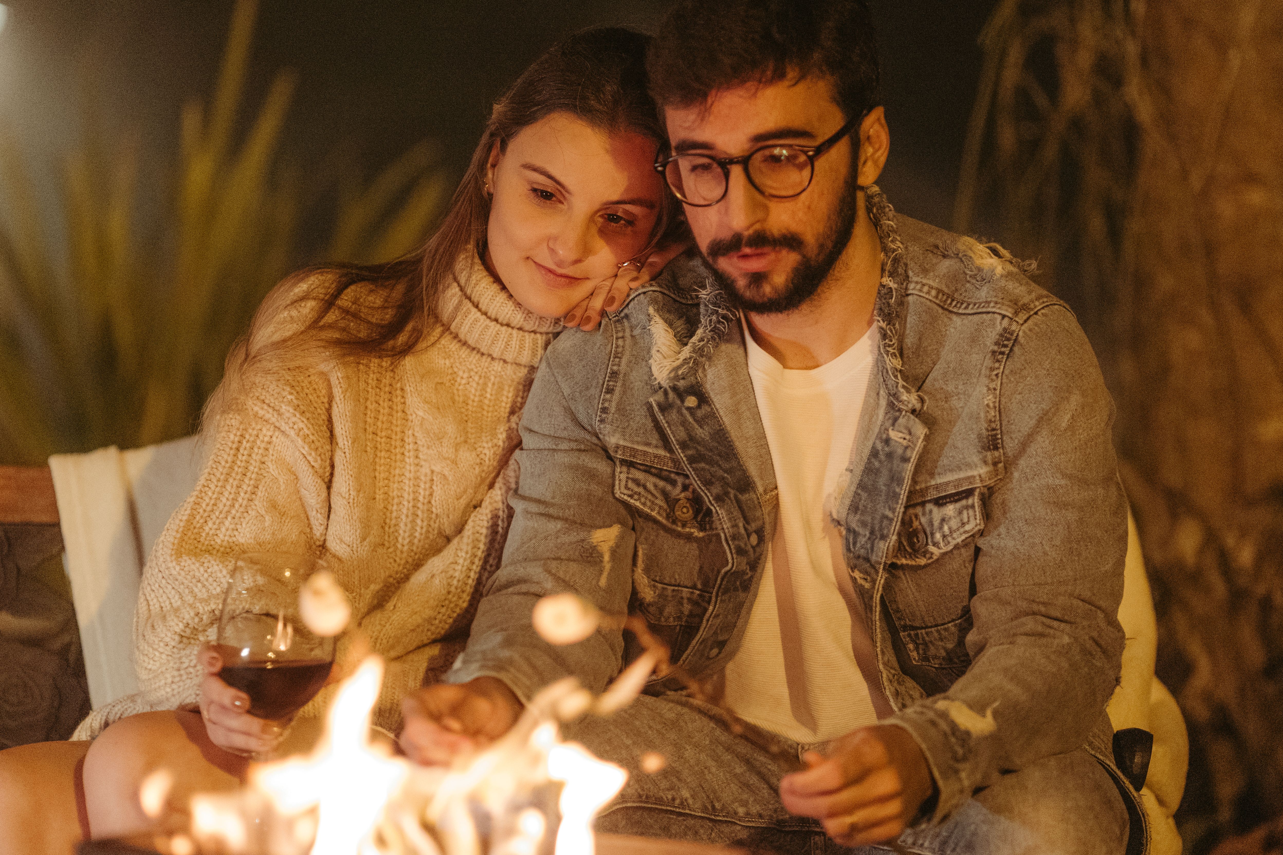 A couple shares a warm moment by the fire, creating a cozy and romantic atmosphere.