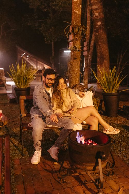 Free A couple enjoys a romantic night by the campfire, smiling and embracing outdoors. Stock Photo