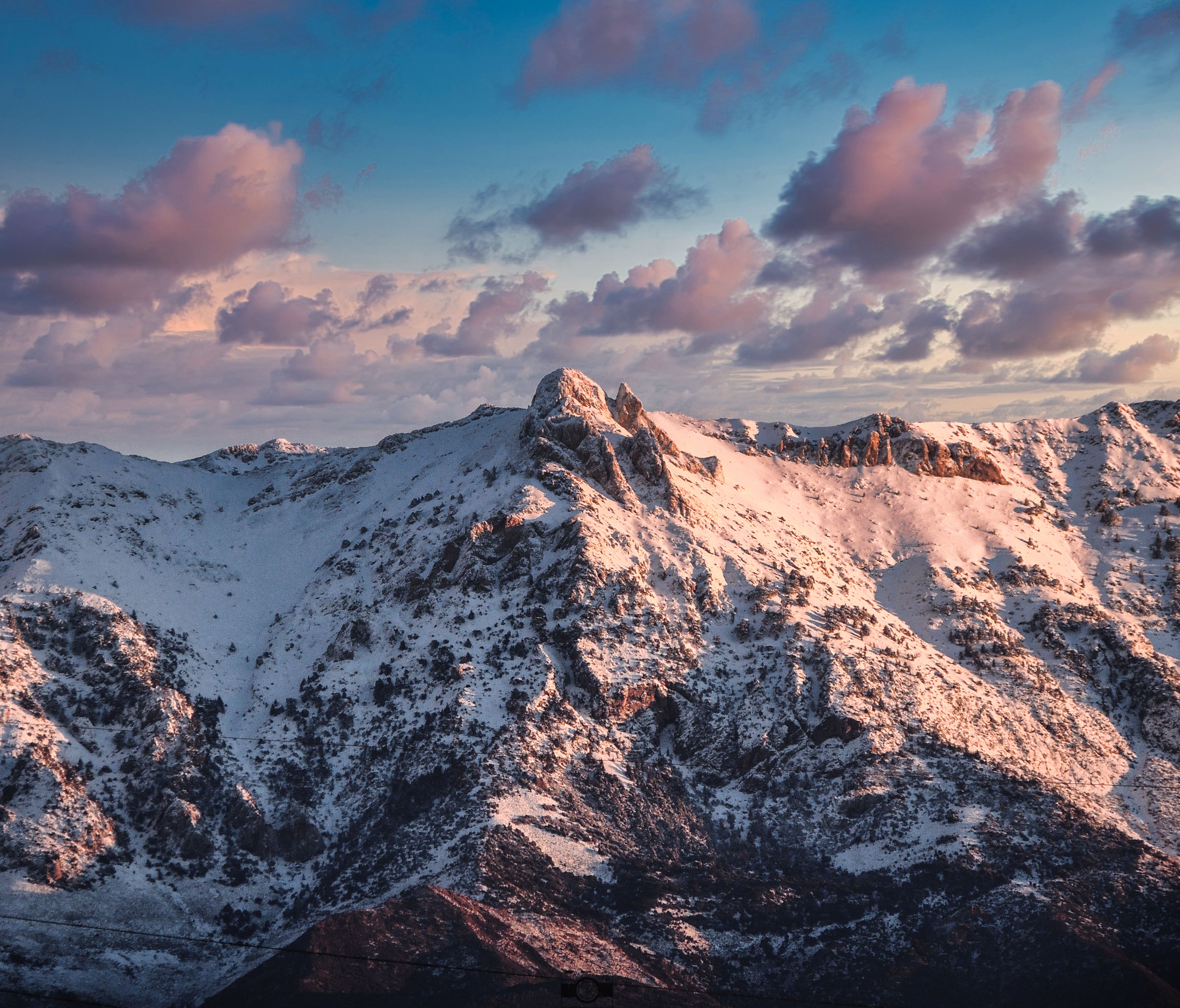 Aerial view of a snow-covered mountain range with a vibrant sunset sky.