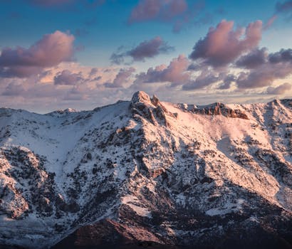 Aerial view of a snow-covered mountain range with a vibrant sunset sky.