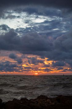 Stunning seascape at sunset with dramatic clouds and ocean waves under a colorful sky.