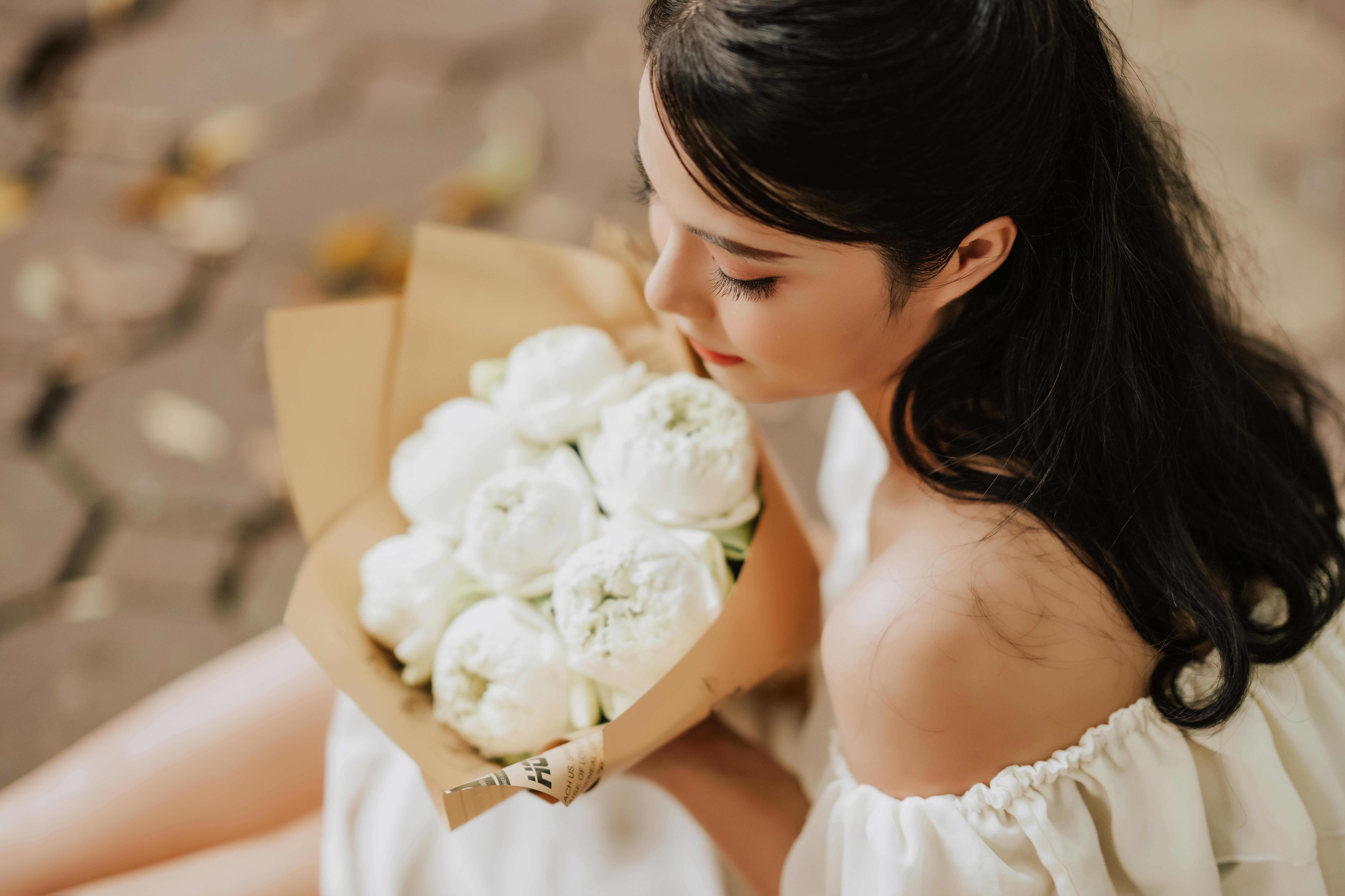 young woman girl getting married in white traditional wedding dress holding  bunch bouquet of white flowers Stock Photo - Alamy