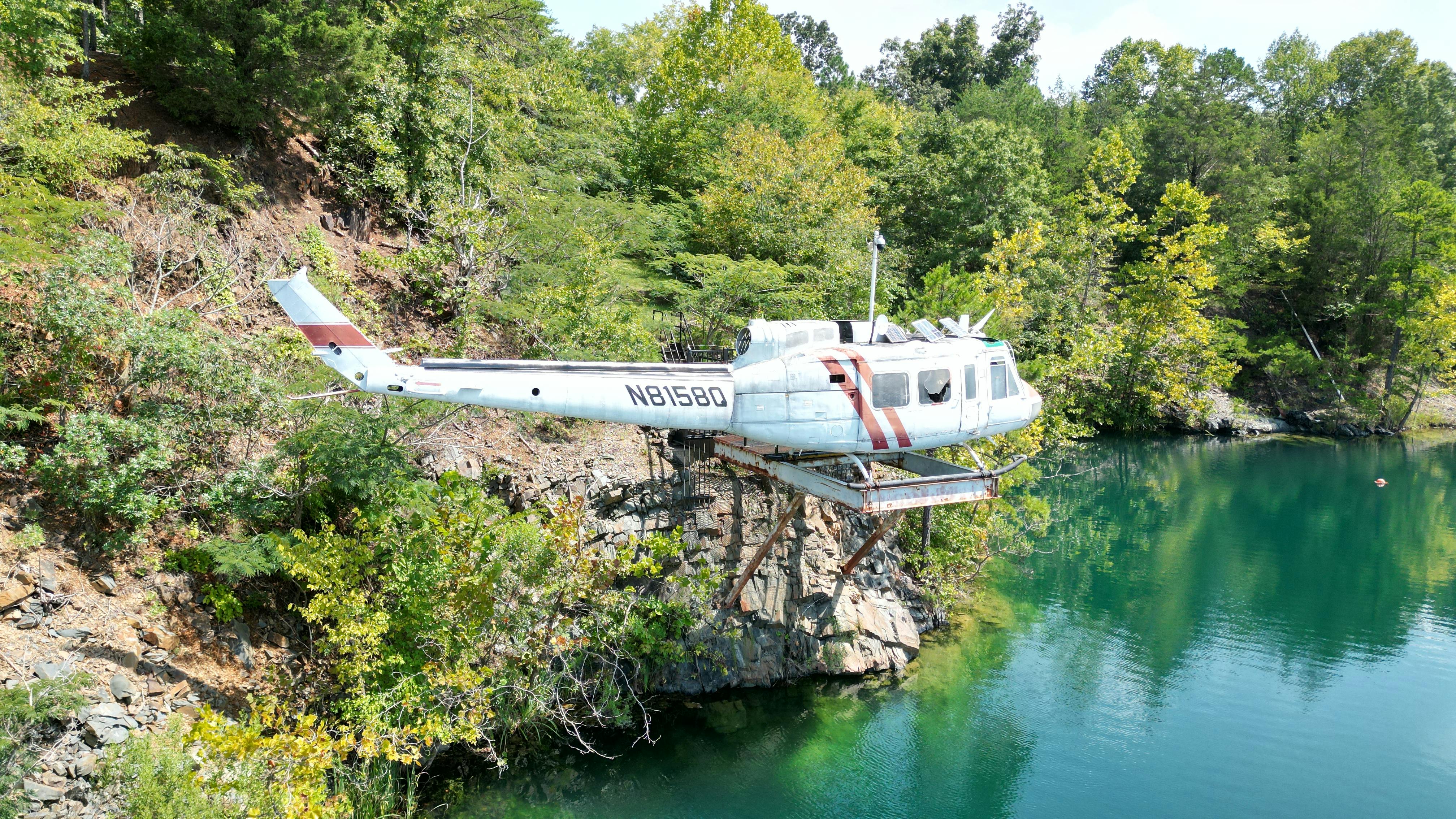 An abandoned helicopter on a cliff surrounded by trees and a lake in Thomasville, NC.