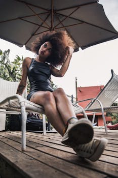 一位优雅的女人撑着雨伞，在露台的躺椅上摆出时髦的姿势