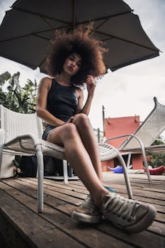 A fashionable woman with afro hairstyle lounging outdoors beneath a parasol.
