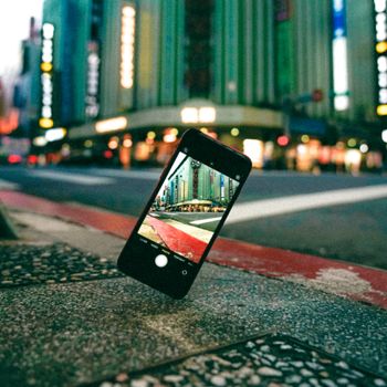 Creative cityscape view through a smartphone screen on a vibrant urban street.